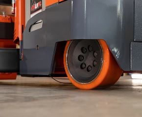 Close-up detail of orange and black forklift wheel and tire with industrial warehouse floor background